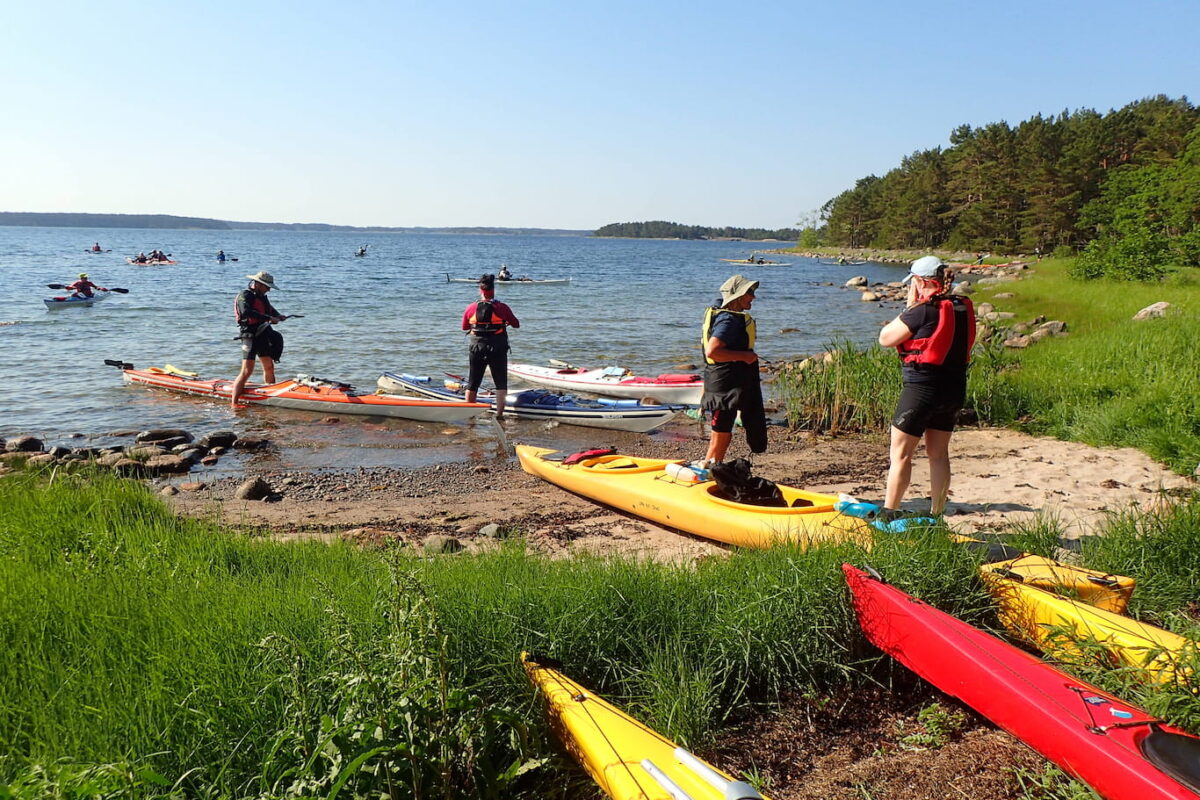 A group of people getting ready to go into the water with their kayaks.