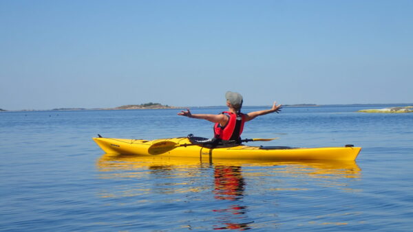 Gabriel on his kayak, looking at the horizon with his arms wide open