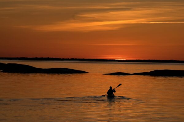 A person paddling towards the horizon on a beautiful orange sunset