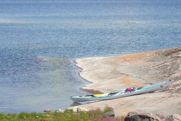 A blue kayak on the shore of a beautiful pastel landscape.