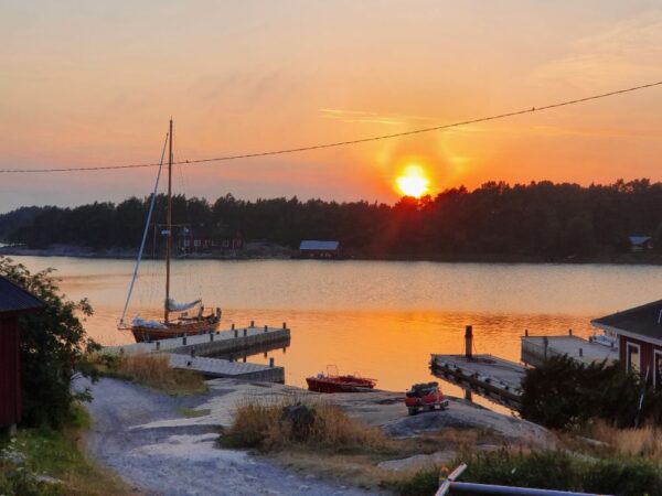 Klippor och segelbåtar vid en vacker solnedgång i Nötö