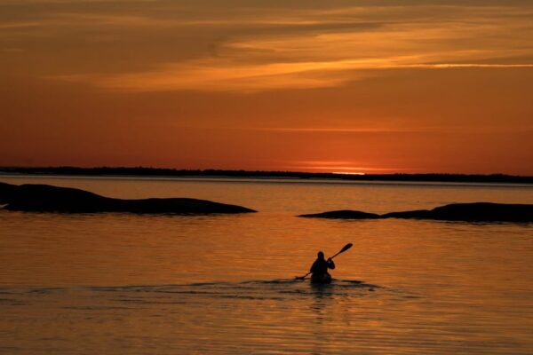 Shilouette av en paddlare på väg mot solnedgången i Skärgårdshavet