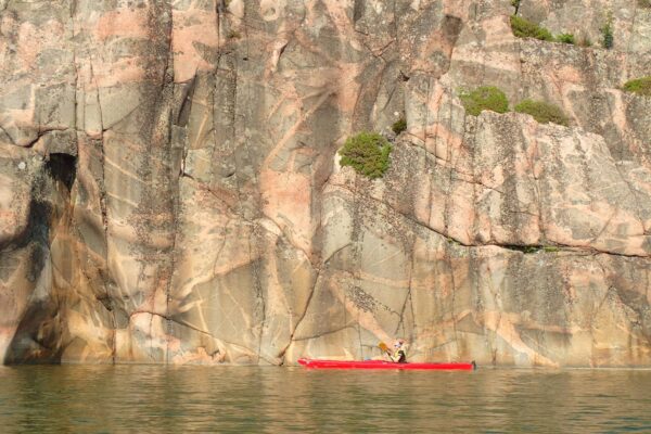 A kayaker in front of a huge rock