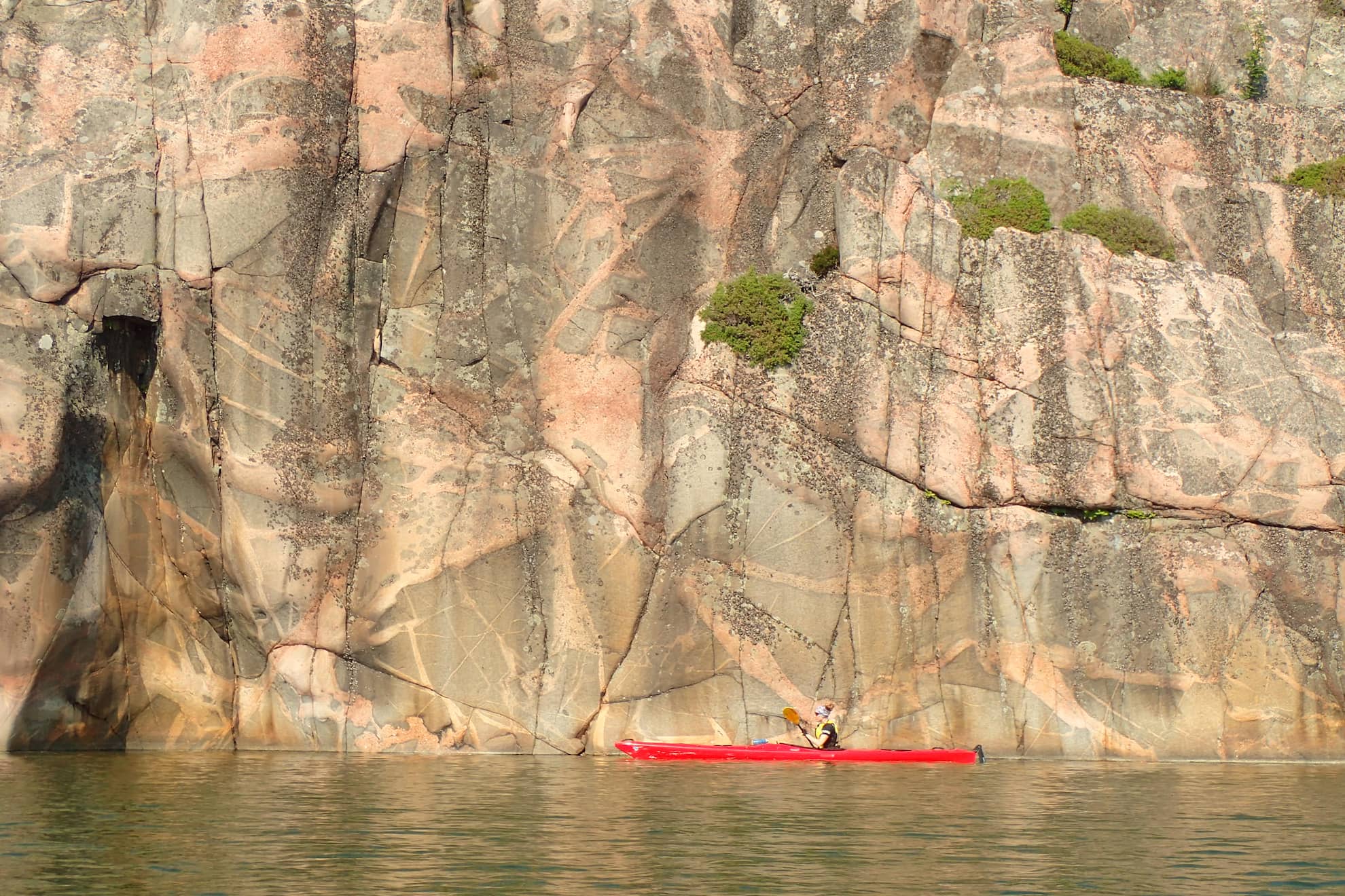 A kayaker in front of a huge rock