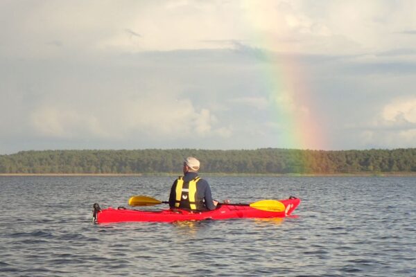 A paddler contemplating a rainbow in the horizon