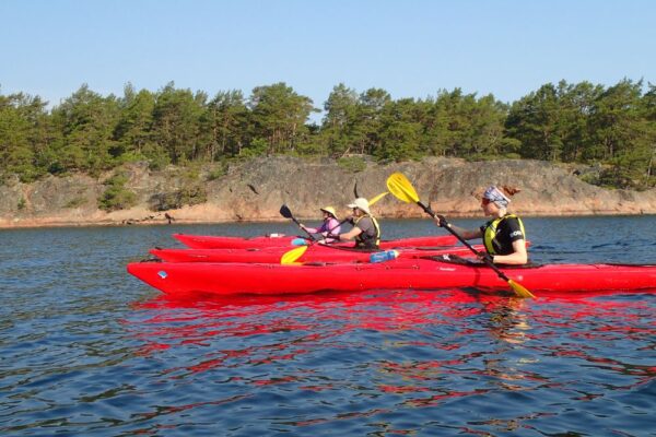 Three paddlers in a row with red kayaks