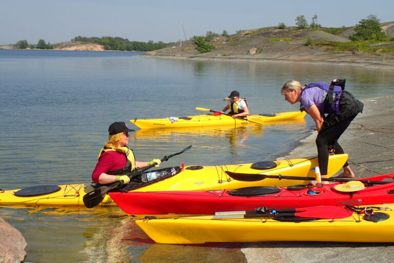 An instructor guiding a kayak student along the shore