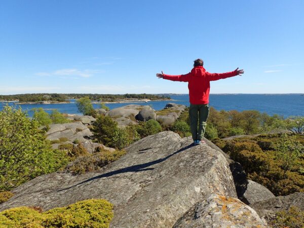 Gabriel står på en klippa med öppna armar och tittar ut mot havet.